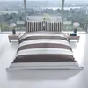 A neatly made bed with striped bedding, set against a large window with a scenic view. Produktbild-Vorschau