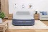 An inflatable air mattress with a headboard is placed in a living room setting. Podgląd zdjęcia produktu