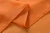 A close-up view of folded orange sheer fabric, likely a curtain, showing the hem and stitching. Produktbild-Vorschau