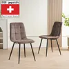 Two brown upholstered dining chairs with black metal legs are shown in a room with a light-colored wall and wooden paneling. Produktbild-Vorschau