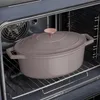 A taupe cast iron Dutch oven with a rose gold knob is placed on a rack inside an oven. Náhľad obrázku produktu
