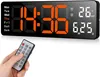 A hand holding a remote control is shown in front of a digital wall clock displaying the time and temperature. Produktbild-Vorschau