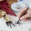 A person's hand is drawing a flower with charcoal sticks. Podgląd zdjęcia produktu