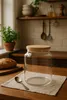 A glass storage jar with a wooden lid sits on a wooden countertop next to a loaf of bread and a spoon. Produktbild-Vorschau