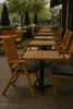 An outdoor seating area with wooden tables and chairs, set up for dining or relaxation. Produktbild-Vorschau