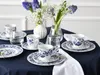 A table set for tea with floral patterned china, glasses, and flowers. Náhľad obrázku produktu