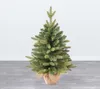 A small artificial Christmas tree in a pot, placed on a wooden floor against a white wall. Voir les images du produit