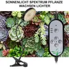 A close-up of a clip-on LED grow light positioned above a collection of succulents. Náhľad obrázku produktu