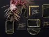 A collection of black and gold New Year's themed party supplies, including plates and napkins, arranged with decorative foliage. Produktbild-Vorschau