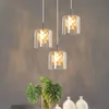 A set of three pendant lights hanging above a table with plants and vases. Produktbild-Vorschau