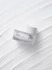 A jar of Anua Heartleaf 70% Intense Calming Cream is placed on a textured white surface. Produktbild-Vorschau