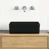 A black ceramic sink is placed on a wooden vanity against a white tiled wall with chrome faucets. Podgląd zdjęcia produktu