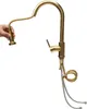 A gold-colored kitchen faucet with a pull-out spray head is shown against a white background. A hand is holding the spray head, demonstrating its flexibility. Podgląd zdjęcia produktu