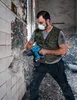 A man is using a power tool to break down a wall in a construction or demolition site. Produktbild-Vorschau