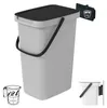 A light gray trash can with a black lid and handle, shown with a measuring cup and a small inset image of the trash can attached to a wall mount. Anteprima dell’immagine prodotto