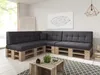 A modern living room with a sectional sofa made of pallets and dark gray cushions, a coffee table made of crates, and a geometric pendant lamp. Produktbild-Vorschau
