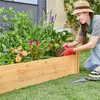 A woman is planting flowers in a raised garden bed. Produktbild-Vorschau