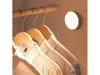 A motion-activated LED night light is mounted on a wall in a closet, illuminating several shirts hanging on wooden hangers. Produktbild-Vorschau