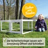 A young girl sits on the grass next to a white outdoor enclosure for small animals, with trees and a blue sky in the background. Produktbild-Vorschau