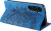 A blue flip case for a smartphone, with a detailed embossed mandala pattern on the front cover. The phone is partially visible inside the case. Produktbild-Vorschau