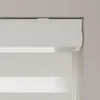 A close-up view of a white roller blind with a cassette headrail, mounted on a wall. Produktbild-Vorschau