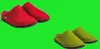 Two pairs of slippers, one red and one green, are shown against a solid green background. Produktbild-Vorschau
