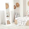 A bedroom scene with a full-length mirror, bed, and decorative hats. Náhľad obrázku produktu