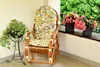 A rocking chair with cushions and plants on a balcony. Produktbild-Vorschau