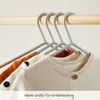 A close-up view of children's clothing hanging on grey hangers on a wooden rod. Anteprima dell’immagine prodotto