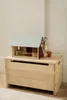 A wooden toy barn and accessories are displayed on top of a wooden toy chest. Produktbild-Vorschau