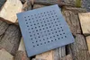 A square metal grate with many circular holes is placed on a pile of chopped firewood. Produktbild-Vorschau