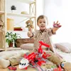A young boy is sitting on the floor playing with a toy airport playset and toy cars. Produktbild-Vorschau