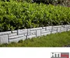 A garden border made of stone-look elements separating a lawn from a hedge. Produktbild-Vorschau