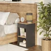 A bedside table with books and a lamp next to a bed and a plant. Náhled obrázku produktu
