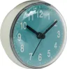 A close-up, slightly angled view of a small, round clock with a teal face and white numbers. Produktbild-Vorschau