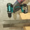 A person is using a Makita cordless drill to drill into a metal bar. Produktbild-Vorschau