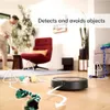 A man is interacting with a robot vacuum cleaner in a living room. The vacuum is shown avoiding various objects on the floor. Náhled obrázku produktu