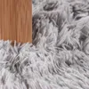 A close-up view of a fluffy gray rug next to a wooden object. Anteprima dell’immagine prodotto