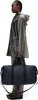 A person is standing and holding a duffel bag. Produktbild-Vorschau