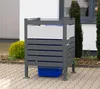 A metal trash bin enclosure with a blue bin inside, placed on a paved patio in front of a building. Náhled obrázku produktu