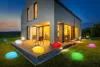 A modern house at dusk with colorful LED garden lights scattered on the lawn and deck. Produktbild-Vorschau