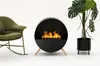A modern living room setup with a rocking chair, a circular fireplace, and a potted plant. Náhled obrázku produktu