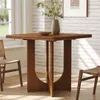 A wooden dining table with chairs in a room with a brick wall and a window. Voir les images du produit