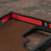 Close-up view of the inside of a dark brown phone case with red accents and a textured brown lining. Anteprima dell’immagine prodotto