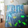 A blue blanket with dinosaur and paw print patterns is draped over a sofa. Anteprima dell’immagine prodotto