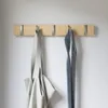 A wooden coat rack with five hooks mounted on a white wall. A grey tote bag and a blue checkered tie are hanging from two of the hooks. Podgląd zdjęcia produktu