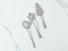 Three pieces of silverware are arranged diagonally on a white marble surface. Anteprima dell’immagine prodotto