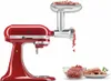 A red KitchenAid stand mixer with a meat grinder attachment is shown, grinding meat into a bowl. A plate of sausages is also visible. Náhled obrázku produktu