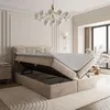 A bedroom scene with a boxspring bed with its storage compartment open, a nightstand, and a chandelier. Produktbild-Vorschau