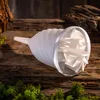 A white filter insert for a funnel is placed on a rustic wooden surface, surrounded by moss and natural elements. Anteprima dell’immagine prodotto